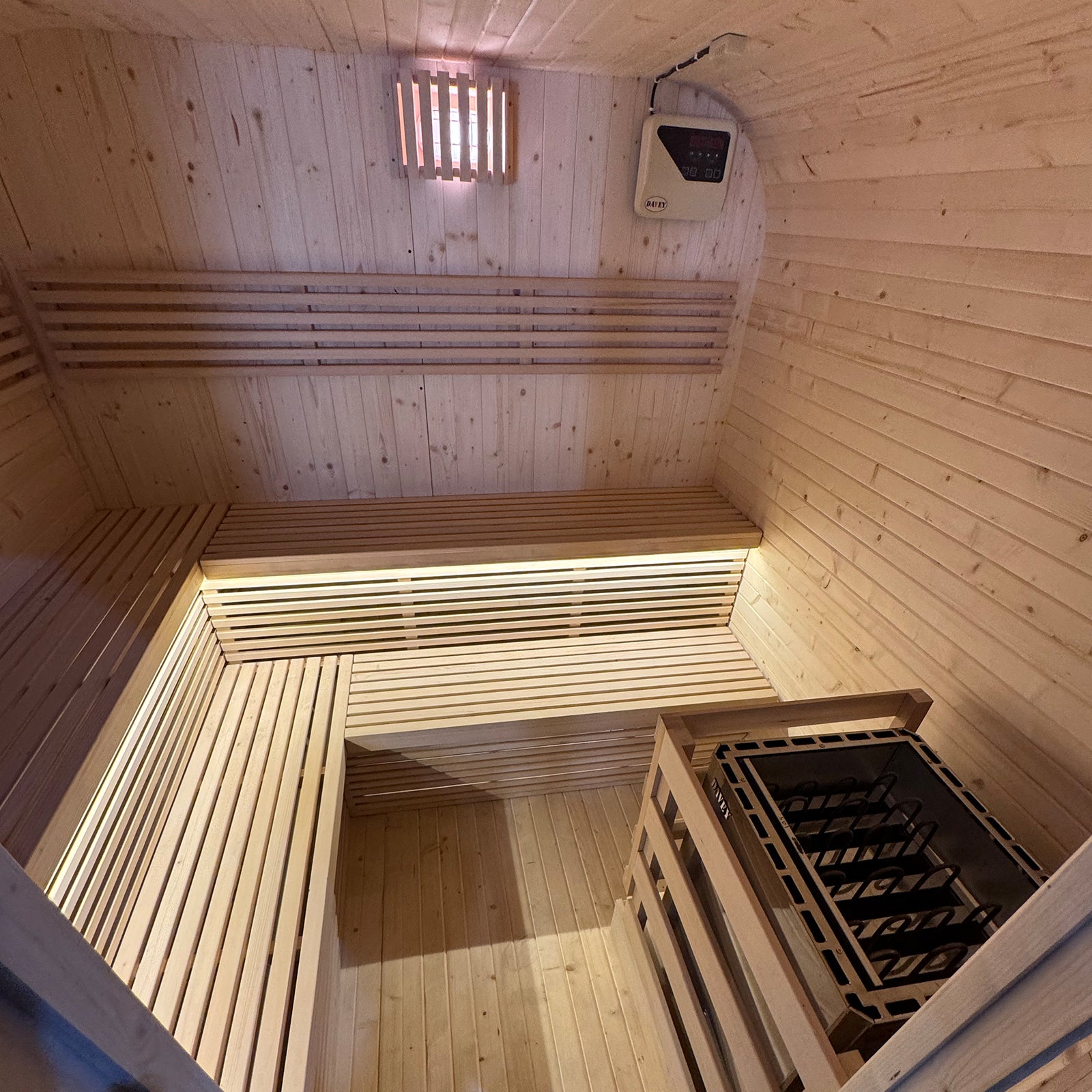 Medika 8 Person Traditional Finnish Outdoor Sauna close-up, showcasing its sleek wooden interior with two-level benches, emphasizing spaciousness and modern design, set inside a wooden sauna environment.