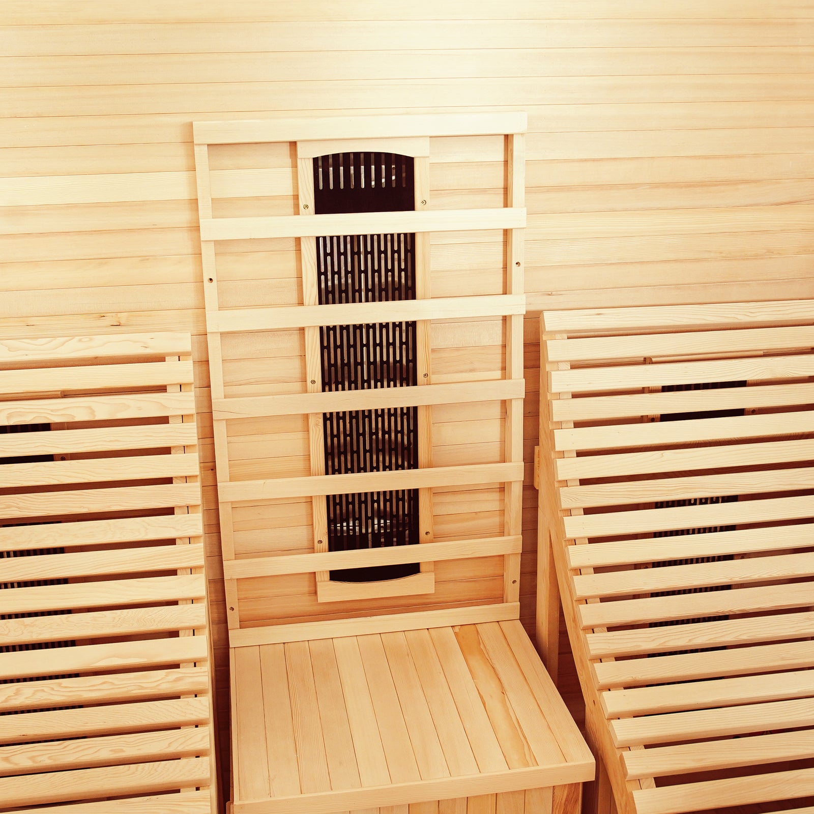 Interior of Metsa 3-Person Hybrid Carbon Fibre Infrared Home Sauna featuring light cedar benches, backrests, and a central black infrared heater panel, showcasing a spacious design for comfort and relaxation.