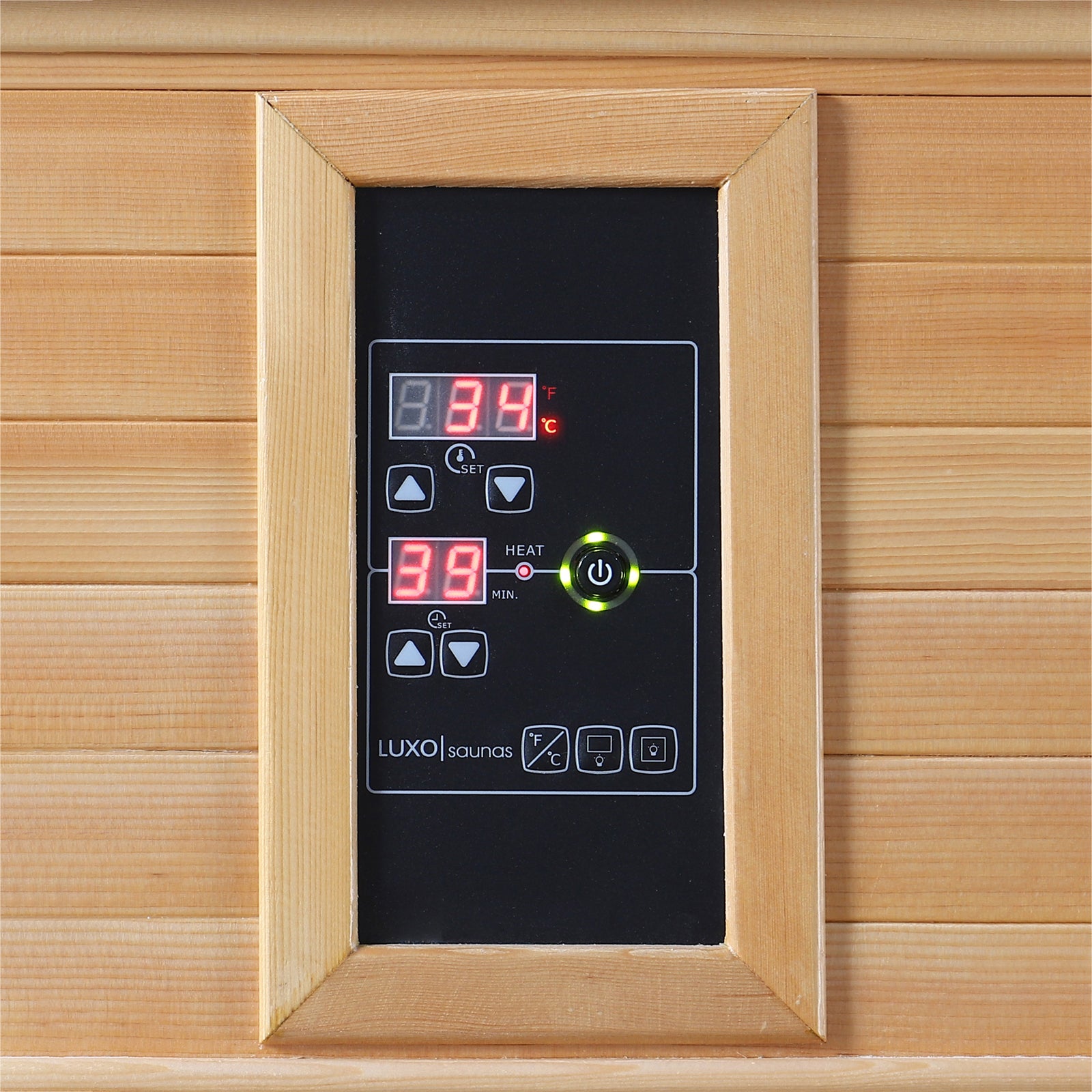 Digital control panel for Metsa 3-Person Hybrid Carbon Fibre Infrared Home Sauna, showing 34°C and 39-minute timer with buttons for temperature, power, and sauna functions, mounted on wood-paneled wall.