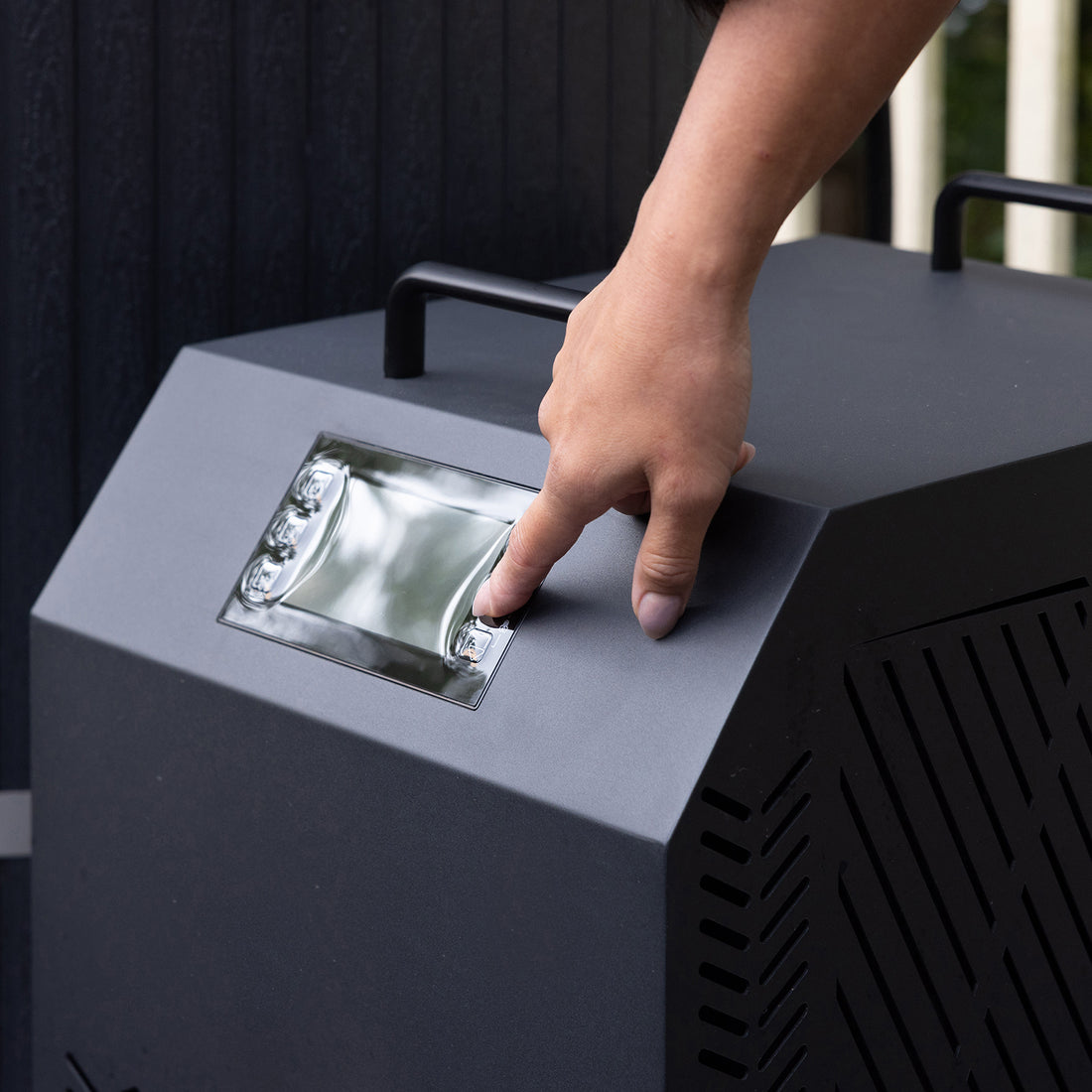 A close-up of a hand interacting with the digital control panel of the Noni 1-Person Outdoor Ice Bath with 1HP Chiller in Black, emphasizing the touch-style buttons and display features.
