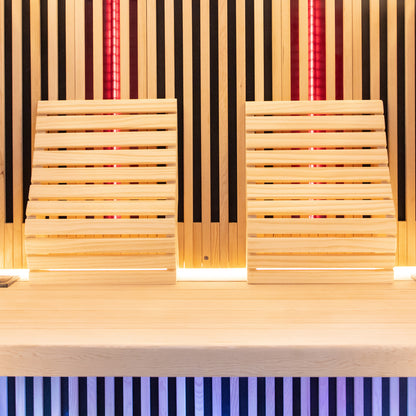 Close-up of the Runko 2 Person Canadian Hemlock Carbon Fibre Infrared Sauna, showcasing its smooth hardwood surface, featuring wooden slats and chairs, highlighting the sauna's craftsmanship and indoor elegance.
