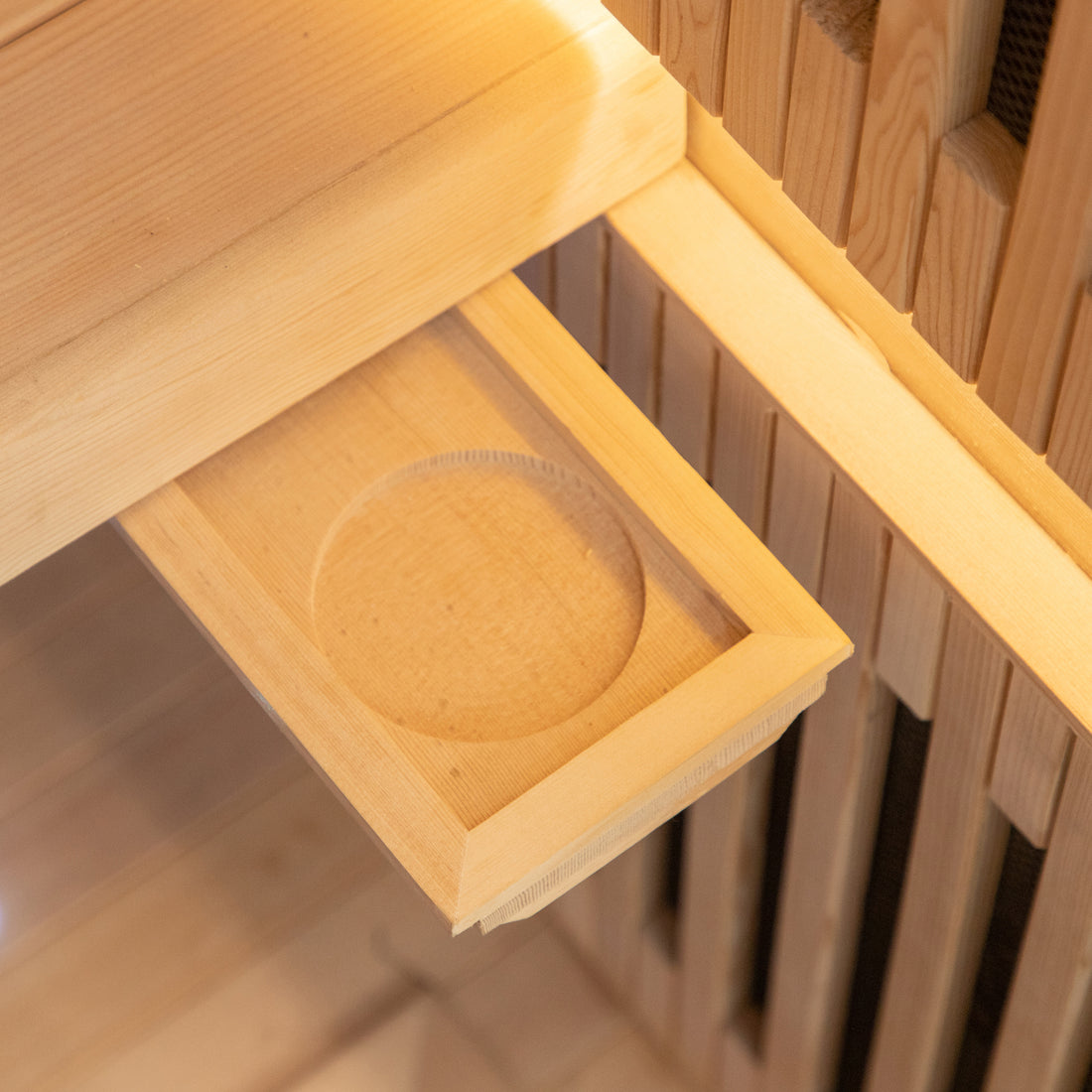 Runko 2 Person Canadian Hemlock Carbon Fibre Infrared Sauna showcased with its smooth, circular wooden exterior, highlighting craftsmanship in woodworking with visible hemlock grain, set on a sturdy wooden shelf.