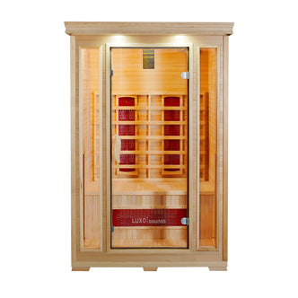 Taavi 2 Person Ceramic Infrared Indoor Home Sauna with light-toned wood, full-glass door, and side panels. Features a bench, infrared heating panels, recessed lights, and Luxo branding on the front.