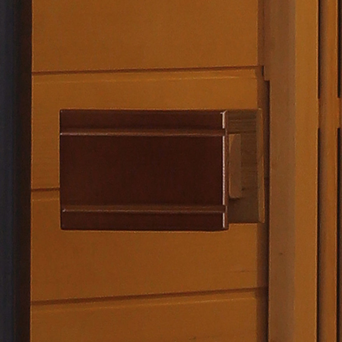 Tumma 2-Person Carbon Fibre Infrared Home Sauna with a rectangular Canadian hemlock construction, featuring a sleek door handle against a wood-paneled wall, designed for indoor relaxation and health benefits.