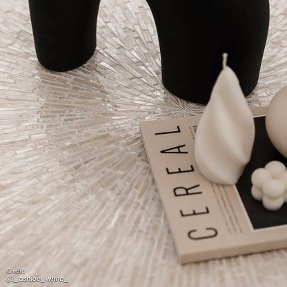 The Abelene 91cm Mother of Pearl Inlay Coffee Table features a hand-crafted mosaic design, with a cylindrical gold pedestal, offering a luxurious art deco accent piece.