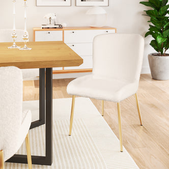 Adela Boucle Fabric Dining Chair Set of 2 in White features off-white bouclé upholstery and slim gold-tone metal legs, adding modern elegance to the dining area with a sleek, contemporary style.