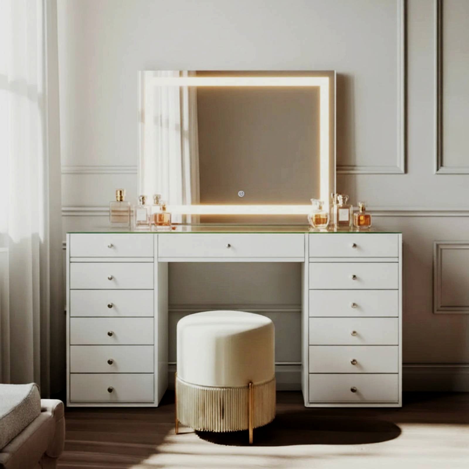 Adeline LED Mirror Storage Dressing Table in White, featuring a wide desk with 13 drawers, a large LED-framed mirror, and a glass top adorned with perfume bottles, paired with a cream stool.