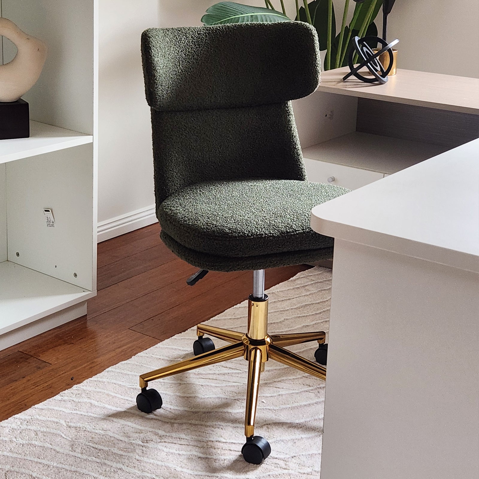 Luxo Aerona High Back Boucle Office Chair in Dark Green features textured upholstery, a curved backrest, polished gold base, and black caster wheels, set in a modern home-office environment.