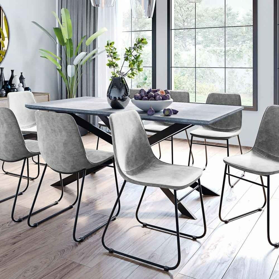 Alfred 180cm 6 Seater Pedestal Dining Table in Concrete, featuring a slim rectangular top and geometric black metal legs, adorned with a dark vase and bowl of purple fruits, set in a bright, modern dining area.