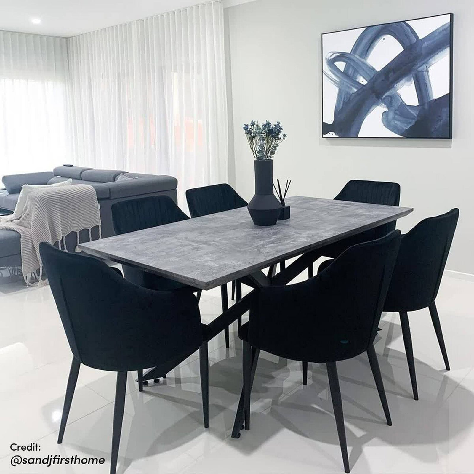 Alfred 180cm 6 Seater Pedestal Dining Table in Concrete with a gray stone-look top and black metal base, surrounded by black upholstered chairs, showcasing contemporary style and functionality.