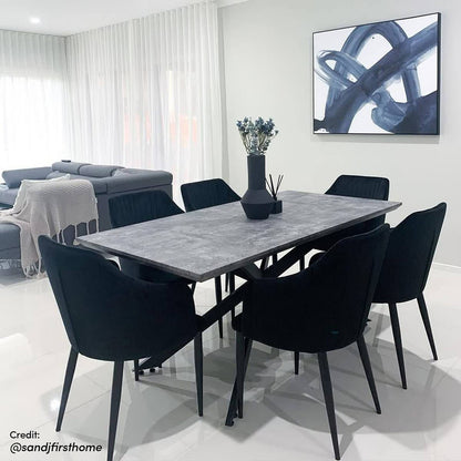 Alfred 180cm 6 Seater Pedestal Dining Table in Concrete with a gray stone-look top and black metal base, surrounded by black upholstered chairs, showcasing contemporary style and functionality.