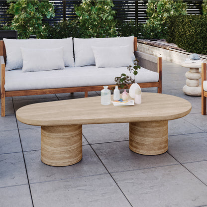 Amarosa Curved Concrete Coffee Table in Beige with a rounded-rectangle top and cylindrical pedestals, adorned with decorative vases, greenery, and books, on a modern outdoor patio.