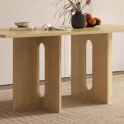 Amora 200cm Dining Table - Natural, showcasing a light-wood finish with two panel legs and oval cut-outs, styled with a black vase, ceramic bowl, and oranges, exuding contemporary elegance.