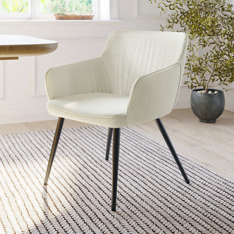 Anthony Linen Dining Chair with Arms Set of 2 in Beige, featuring light-cream upholstery, curved back, and black-metal legs, set in a minimalist room with a textured rug and potted plant.