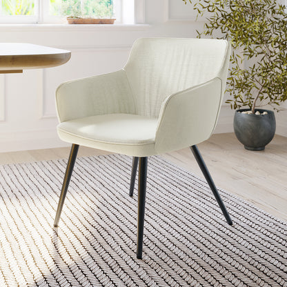 Anthony Linen Dining Chair with Arms Set of 2 in Beige, featuring light-cream upholstery, curved back, and black-metal legs, set in a minimalist room with a textured rug and potted plant.