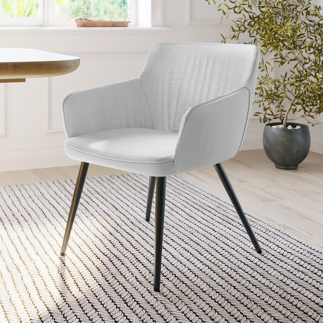 Anthony Linen Dining Chair with Arms Set of 2 in Light Grey, featuring light gray upholstery, black metal legs, set beside a wooden table on a neutral rug, with a potted plant nearby.