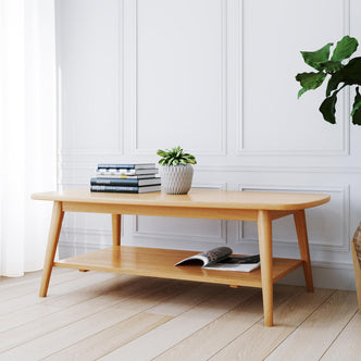 Asher 120cm American Oak Coffee Table Natural with tapered legs, featuring a white ceramic planter and books on top, open magazine below, highlighting mid-century and Scandinavian-inspired design in a minimalist setting.