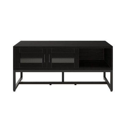 Ashley Coffee Table with Fluted Glass Door in Black features a matte black finish, vertical ribbed panels, and an open cubby, sitting on a minimalist metal frame for a modern-industrial look.
