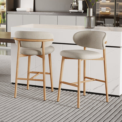 Audrey Curved Dining Chair & Bar Stool Bundle features light wood frames, beige curved upholstery, and padded seats, enhancing a marble-veined island with a metallic vase in a modern kitchen setting.