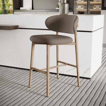 Audrey Velvet Fabric Upholstered Barstool Set of 2, featuring a light wood frame with curved backrest and padded seat, elegantly positioned at a white marble kitchen island in a modern setting.