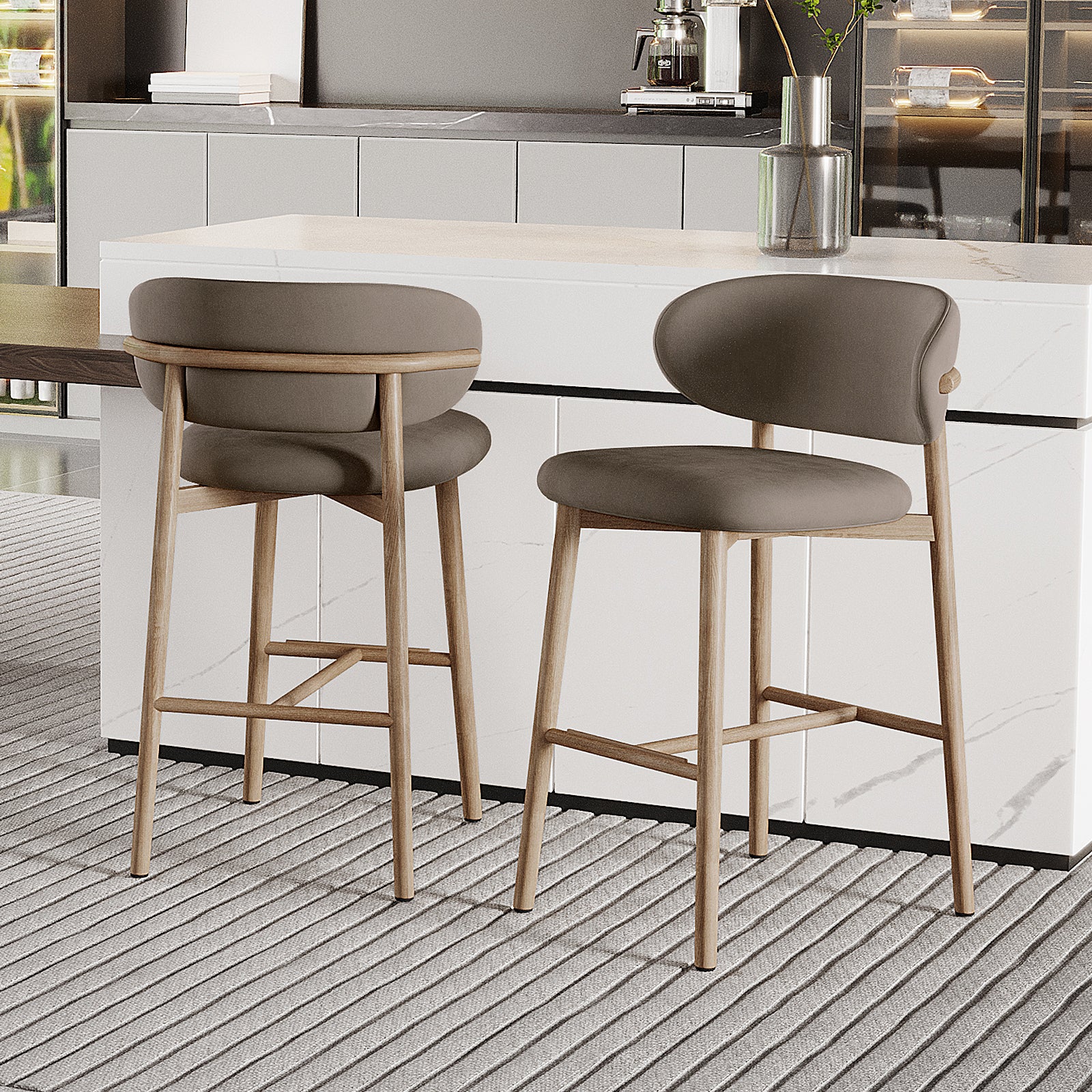 Audrey Velvet Fabric Upholstered Barstool Set of 2 with grayish-taupe curved backs, light wood legs, and a white marble counter, complementing a modern kitchen with a coffee maker and plant vase nearby.