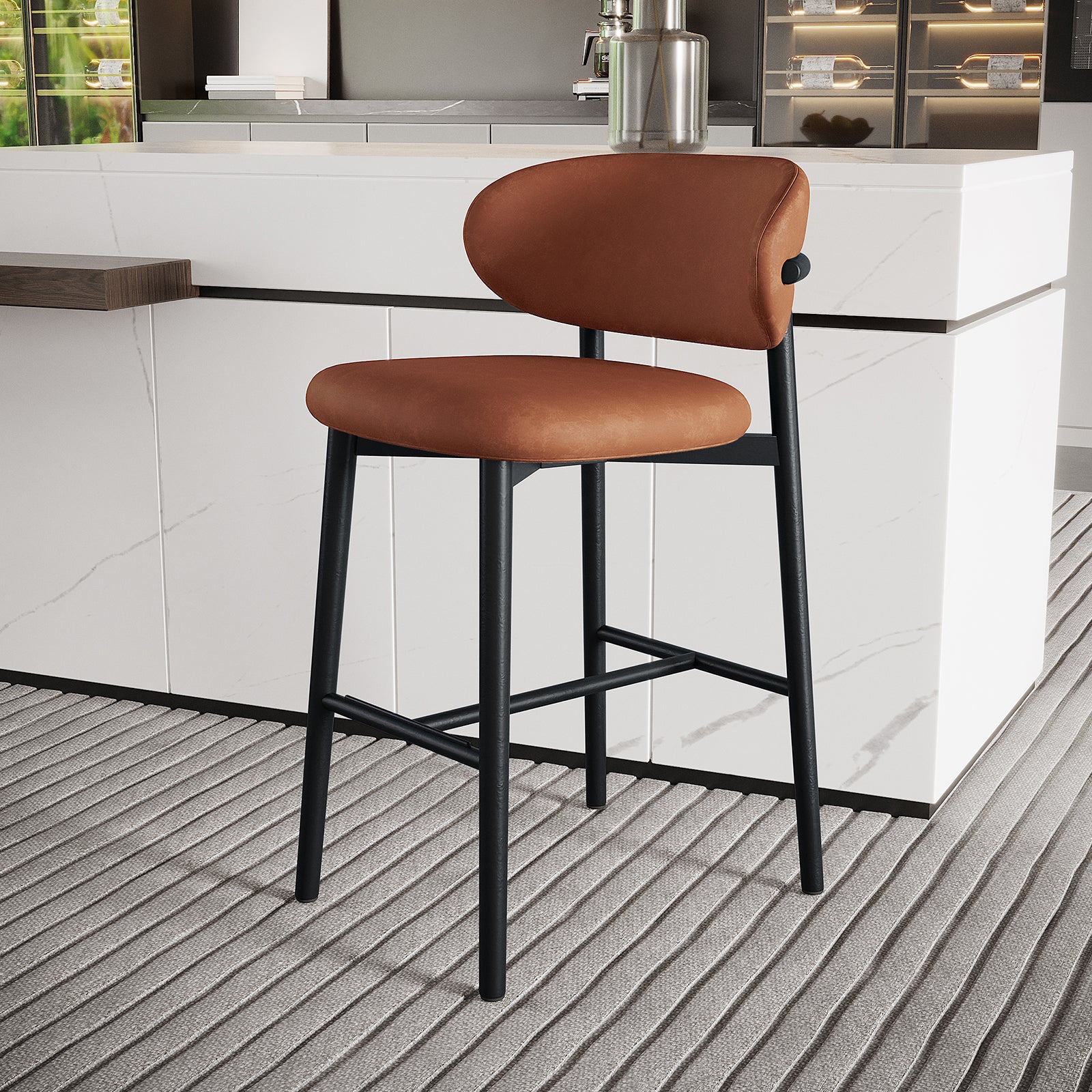 Audrey Curved PU Leather Barstool Set of 2 in Tan features a burnt-orange upholstered seat and backrest on sleek black metal legs, placed at a white marble-veined kitchen island.