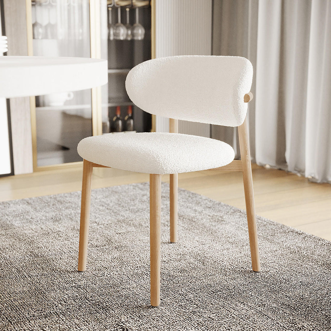 Audrey Curved Fabric Dining Chair Set of 2 in Cream White, featuring softly rounded bouclé upholstery and light-wood legs, positioned on a charcoal-grey rug in a modern dining space.
