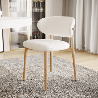 Audrey Curved Fabric Dining Chair Set of 2 in Cream White, featuring softly rounded bouclé upholstery and light-wood legs, positioned on a charcoal-grey rug in a modern dining space.