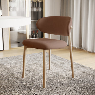 Audrey Fabric Dining Chair Mocha Mouses Set of 2 features a curved padded seat and backrest in a warm brown leather-like material on a light oak frame, set in a softly lit dining room.