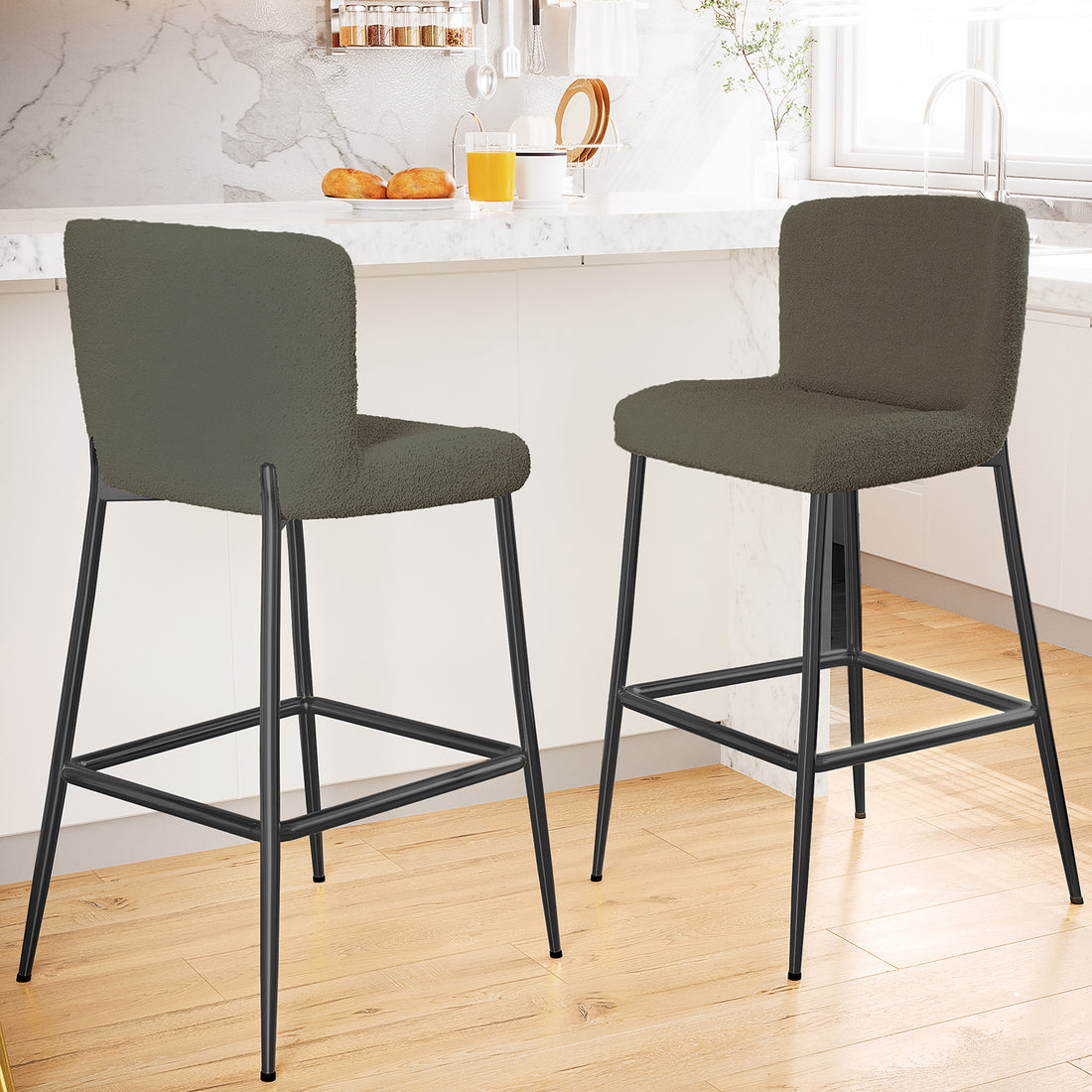 Bernie High Back Boucle Bar Stool Set of 2 in Green, featuring softly upholstered backs and seats, slender black metal legs, and a built-in footrest, complementing a modern kitchen island scene.