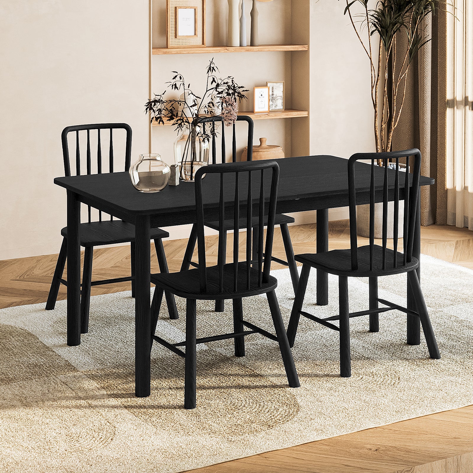 Luxo Living Bijan extendable solid oak dining table and four Leigh solid oak spindle-back chairs in a black finish, placed on a textured rug in a contemporary dining space with warm lighting.