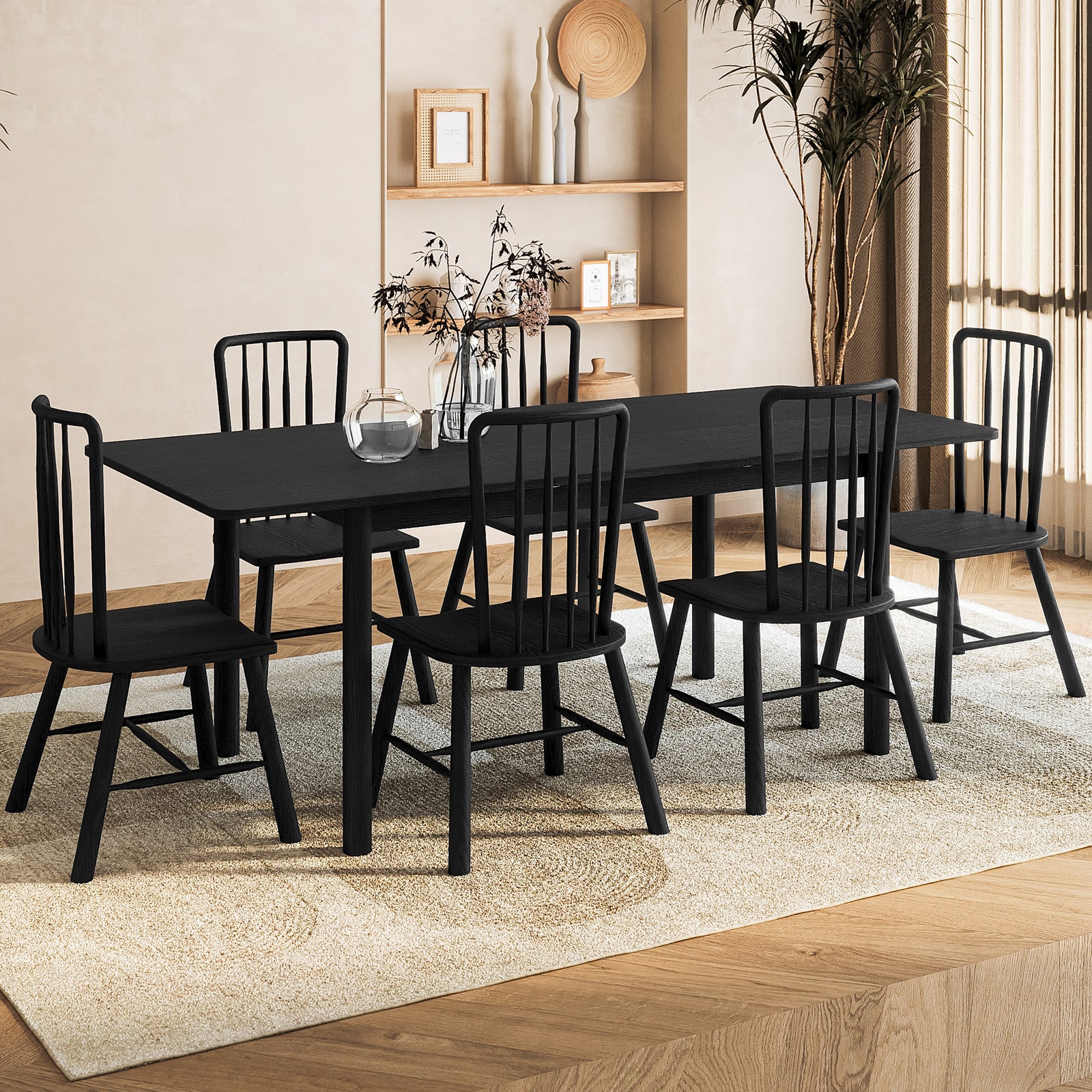 Luxo Living Bijan extendable solid oak dining table and six matching Leigh solid oak spindle-back chairs in a stylish black finish, set in a modern dining room with a neutral rug and decorative shelves."