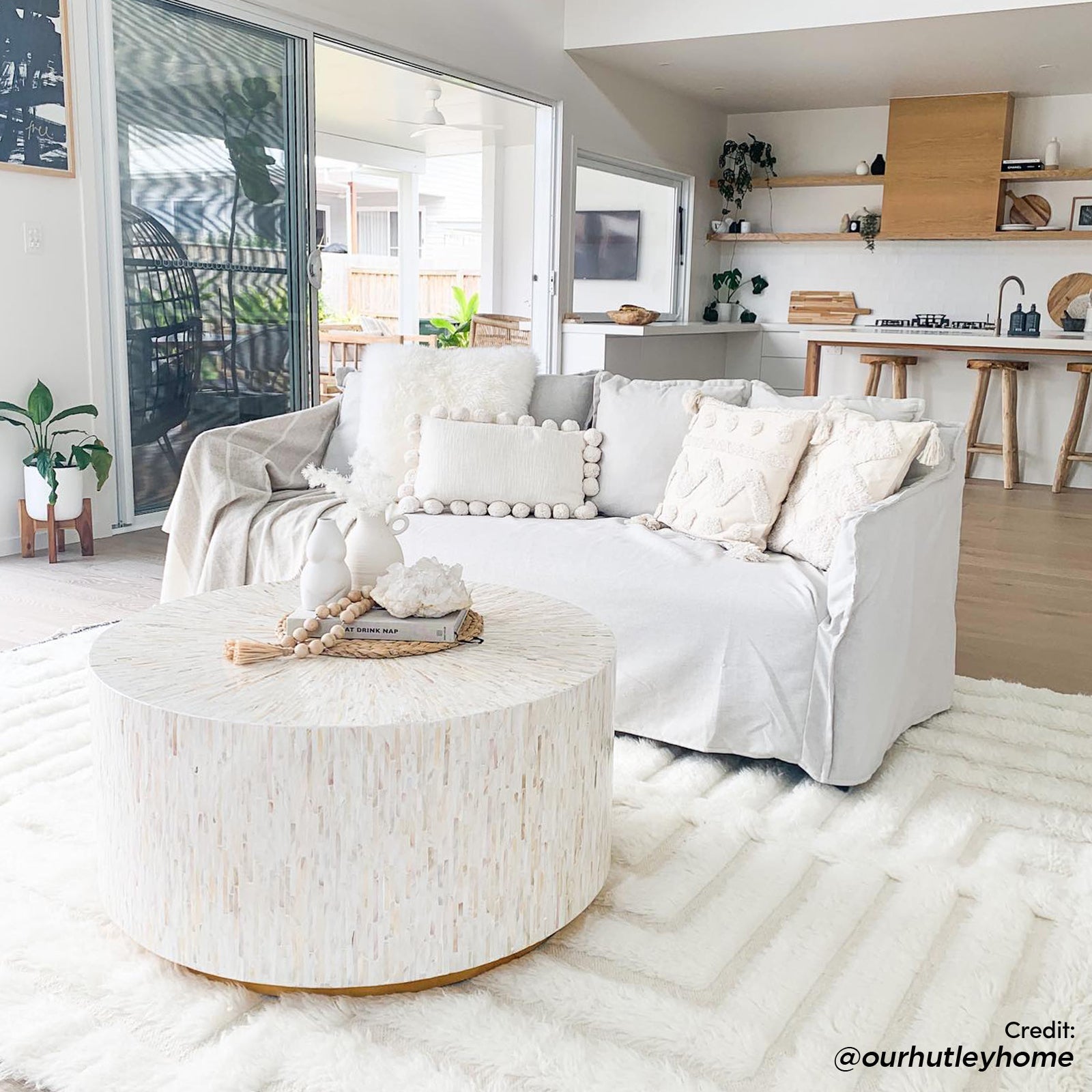 Bisera 91cm Mother of Pearl Inlay Coffee Table, featuring a hand-crafted mosaic design, sits elegantly in a living room setting with a couch and pillow, highlighting its luxury and craftsmanship.