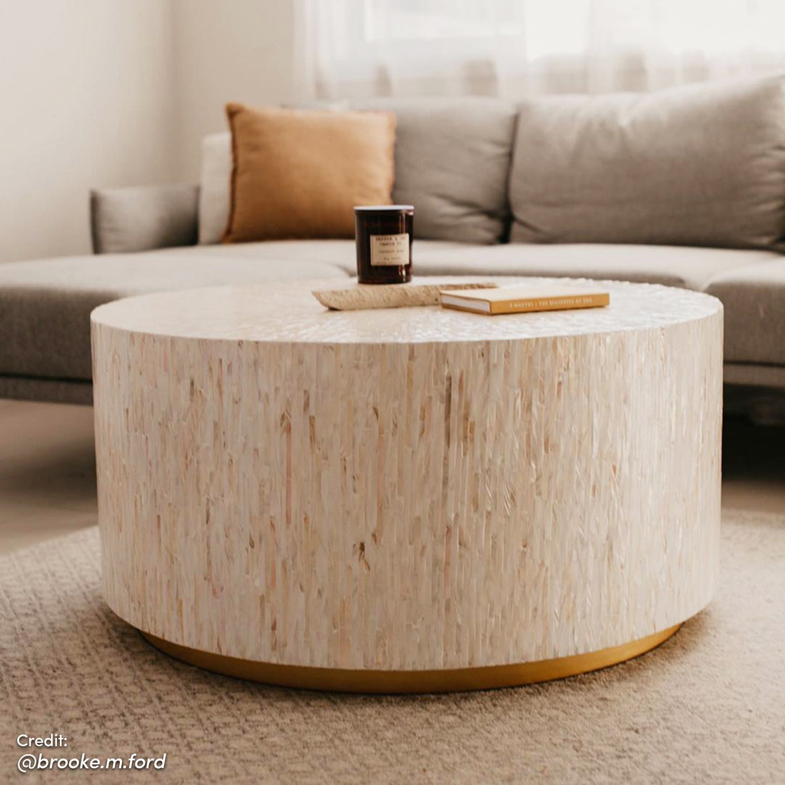 Bisera 91cm Mother of Pearl Inlay Coffee Table features intricate hand-crafted mosaic tiles on a sturdy base, positioned near a candle and book, highlighting its elegant design and craftsmanship.