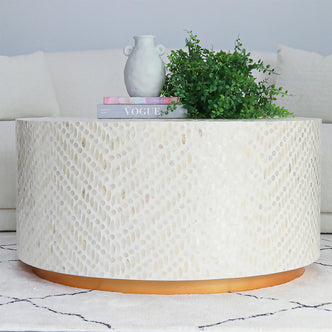 Bisera 91cm Mother of Pearl Inlay Coffee Table features a round top with intricate mother-of-pearl mosaic, situated on a sturdy base, positioned in an elegant indoor setting.