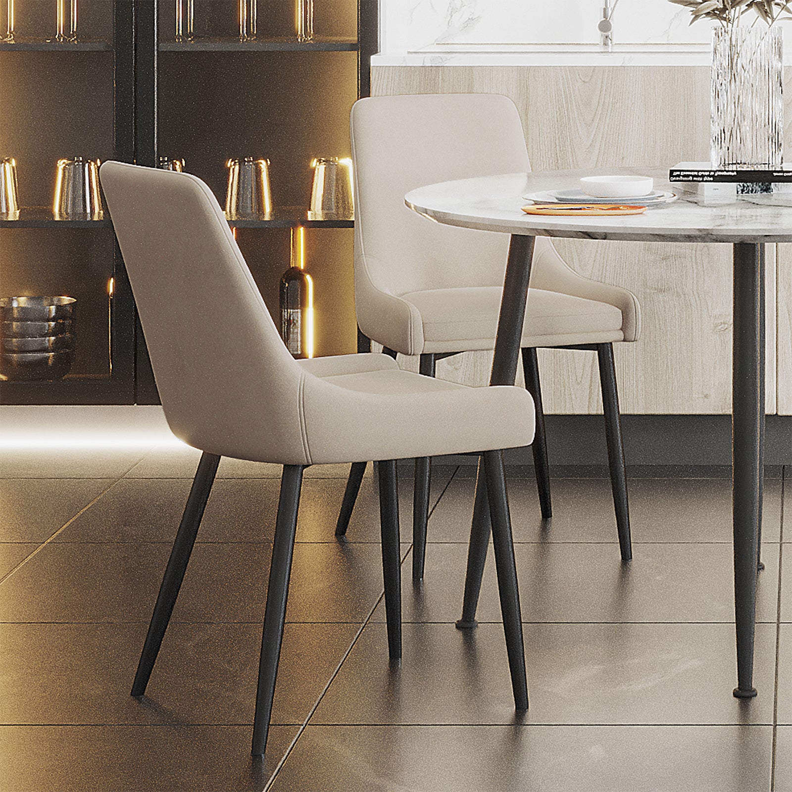 Blythe High Back Fabric Dining Chair Set of 2 in Beige, featuring light-colored upholstery and sleek black metal legs, positioned around a marble-look table in a modern dining nook setting.
