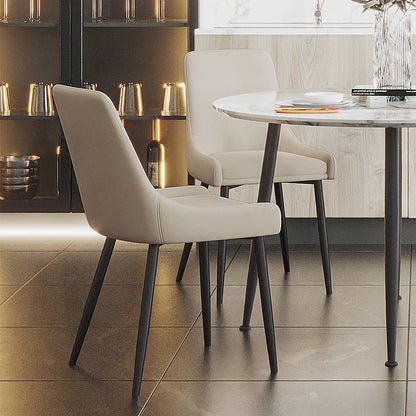 Blythe High Back Fabric Dining Chair Set of 2 in Beige, featuring light-colored upholstery and sleek black metal legs, positioned around a marble-look table in a modern dining nook setting.