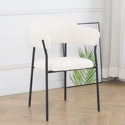 Clavin Boucle Dining Chair Set of 2 in Cream White, featuring softly rounded bouclé upholstered seats and backrests with slender black metal legs, against a light wall with a framed palm leaf print.