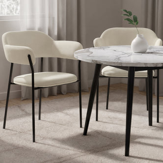 Clavin Fabric Dining Chair Set of 2 in Light Beige, featuring cream upholstery on slender black metal legs, with gently curved backs and seat pads, surrounding a modern marble-effect table.