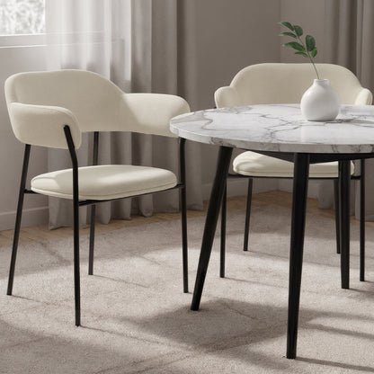 Clavin Fabric Dining Chair Set of 2 in Light Beige, featuring cream upholstery on slender black metal legs, with gently curved backs and seat pads, surrounding a modern marble-effect table.