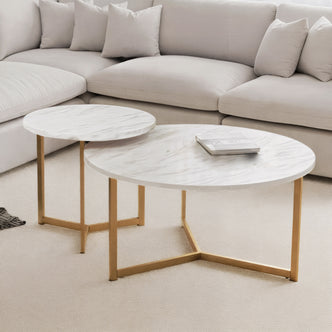 Earl Nesting Coffee Table Set with Gold Legs in Marble, featuring two round tables with white marble tops and gold-finish legs, complements a beige sectional sofa and carpet.