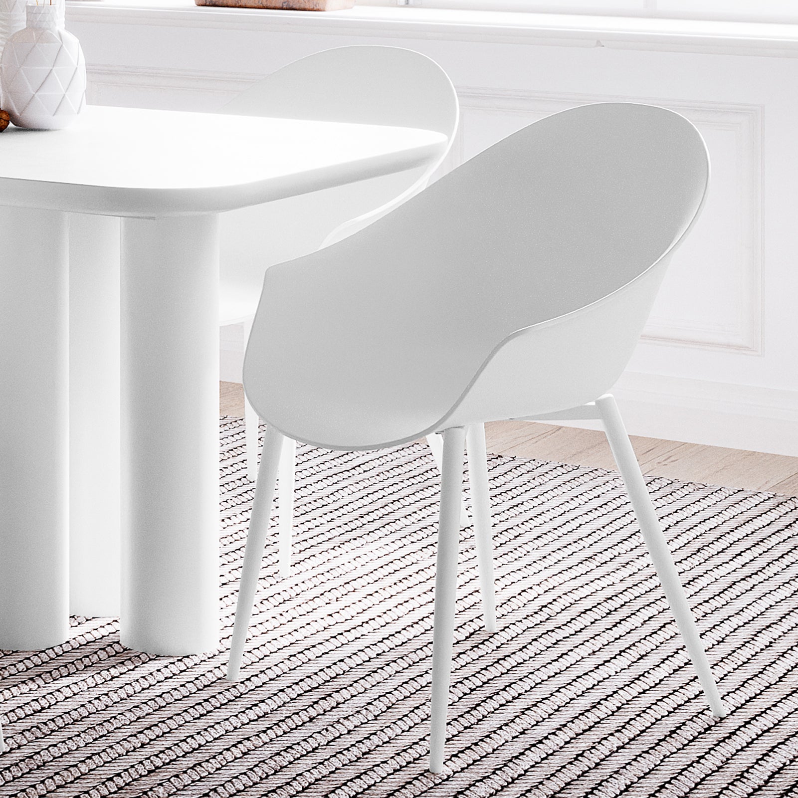Eidos Indoor/Outdoor Modern Plastic Dining Chair w/ Armrest White Set of 2 displayed on a rug, showcasing its sleek design and armrests, perfect for enhancing indoor or outdoor dining spaces.