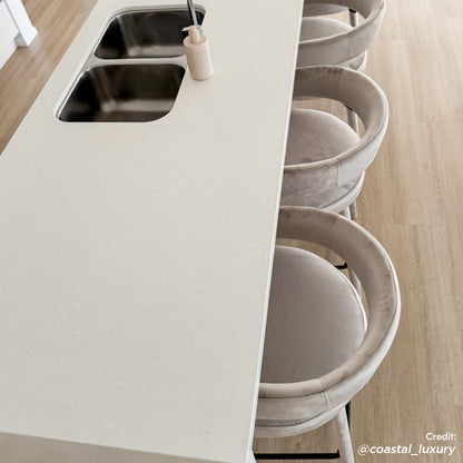 Eisha Velvet Bar Stool Set of 2 in Beige, featuring plush velvet upholstery, curved backrests, and sturdy powder-coated metal legs, elegantly tucked under a modern kitchen island with a white quartz countertop.