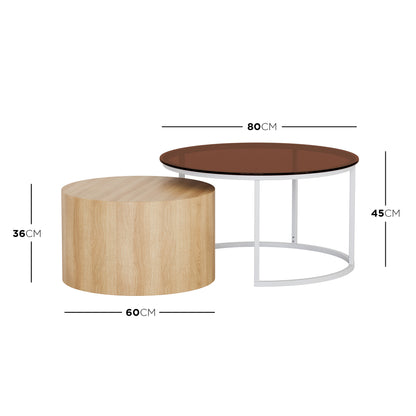 Ellisha Round Nesting Coffee Table in Natural features a small light oak-tone wood veneer table and a larger white steel-framed table with a smoked brown glass top, offering stylish versatility.