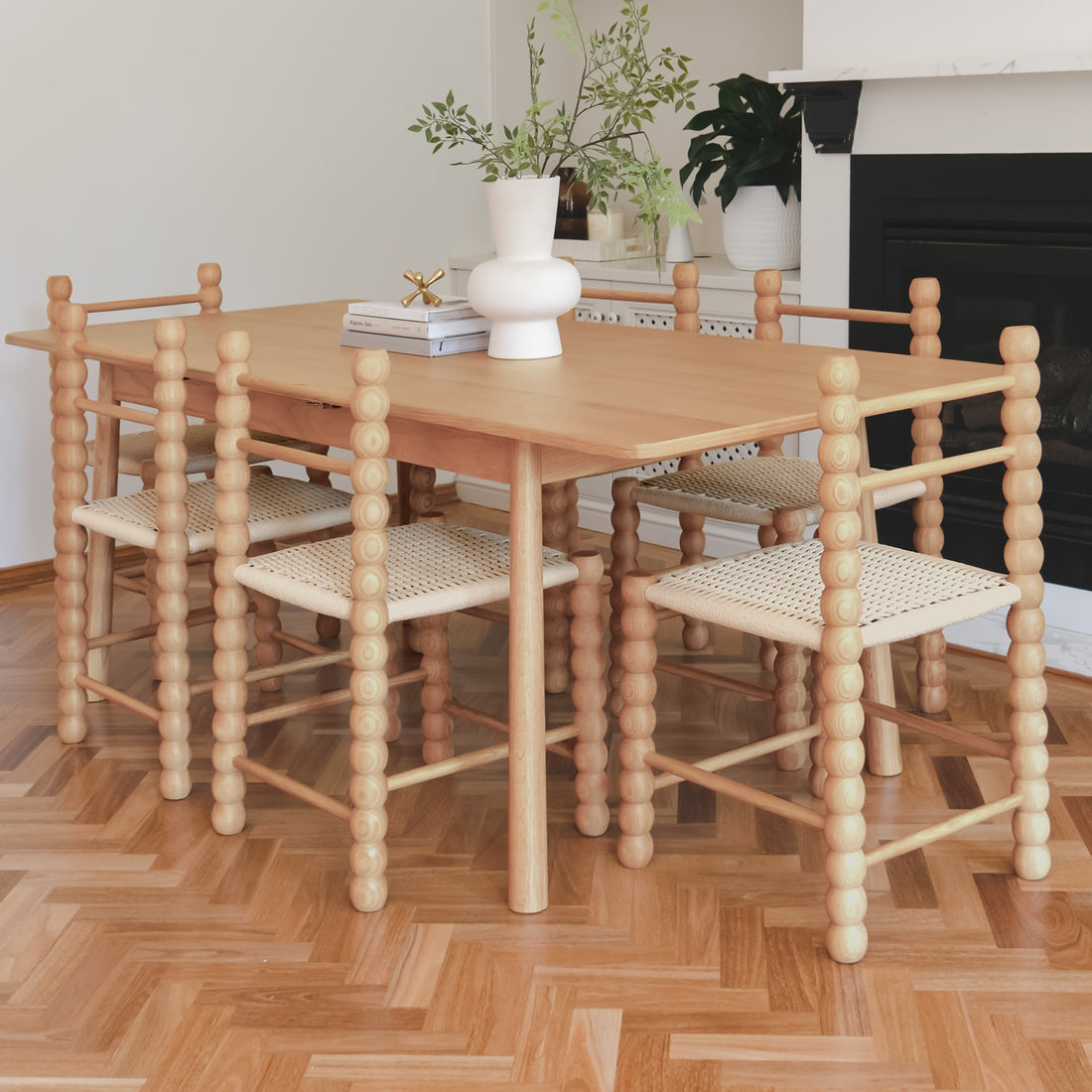 Em Solid Oak Dining Chair Set of 2 - Natural showcased around a wooden table, featuring distinctive beaded posts and woven seats, enhancing the light-filled dining area with rustic charm and modern appeal.