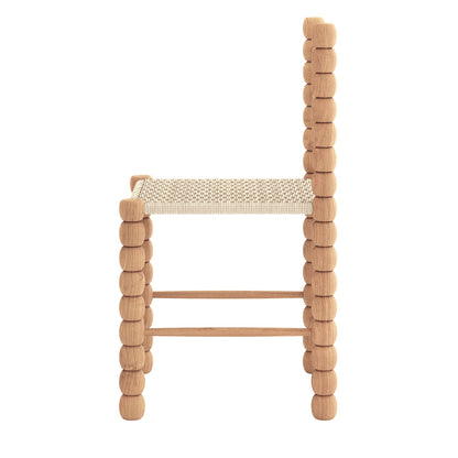 Side-view of the Em Solid Oak Dining Chair Set of 2 - Natural, featuring a bobbin-style frame with rounded wooden elements and a woven fiber seat, showcasing modern and rustic design elements.