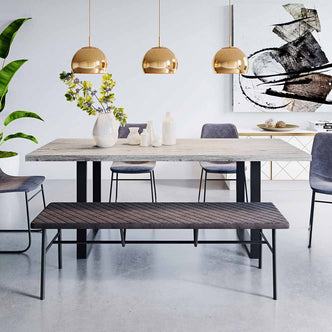 Ernest 200cm 6 Seater Industrial Dining Table in Natural, featuring a rectangular light-gray wood tabletop with black metal U-shaped legs, complemented by matching bench and upholstered chairs, under brass pendant lights.