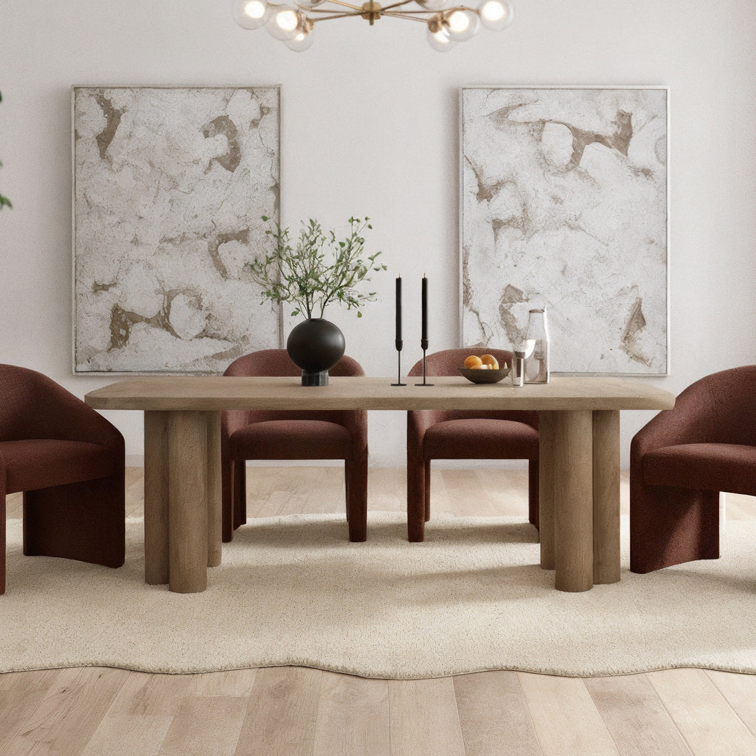 Faunus 200cm 8 Seater Dining Table in Natural with chunky cylindrical legs, centered on a pale rug, surrounded by rust-upholstered chairs, adorned with a black vase, candles, and a fruit bowl.