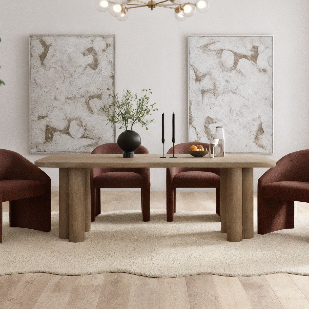 Faunus 200cm 8 Seater Dining Table in Natural with chunky cylindrical legs, centered on a pale rug, surrounded by rust-upholstered chairs, adorned with a black vase, candles, and a fruit bowl.