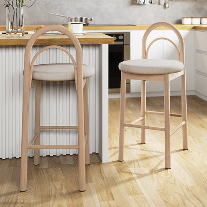 Gilles Linen Arched Bar Stool Set of 2 - Beige, featuring a curved backrest and built-in footrest, displayed close to a counter, showcasing its modern metal frame and wood veneer details.